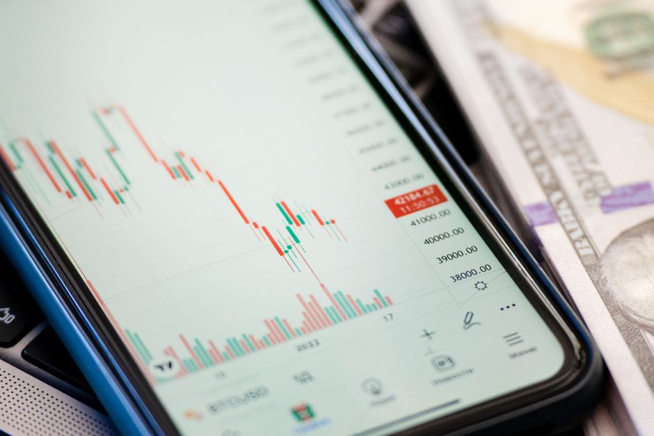 Detailed view of stock market data on a smartphone with US dollars in the background, illustrating trading.